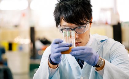 Jack Wang studies three test tubes in a holder in a laboratory